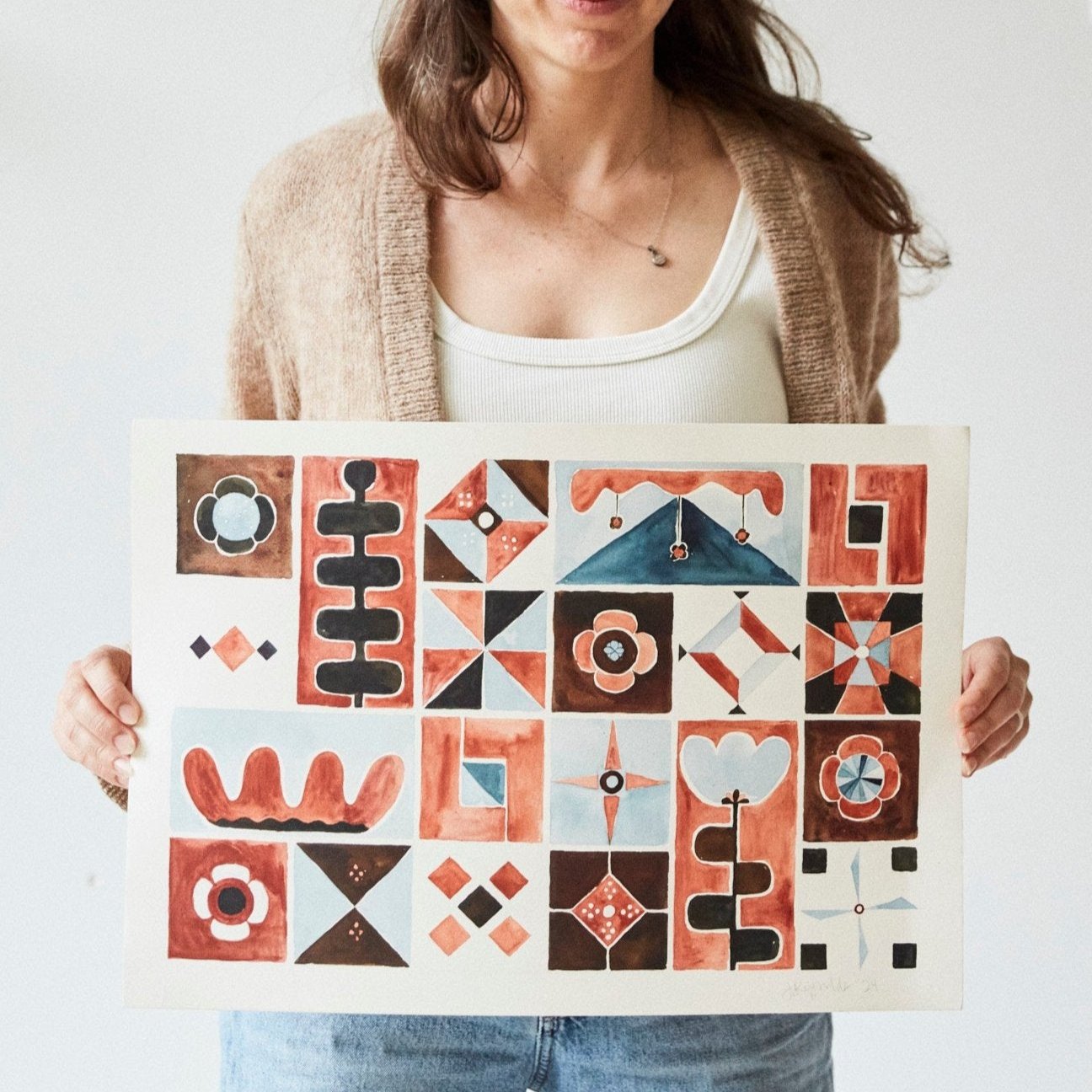 Austin watercolor artist Jaime Reynolds holds her folk patchwork terra cotta chestnut blue original painting